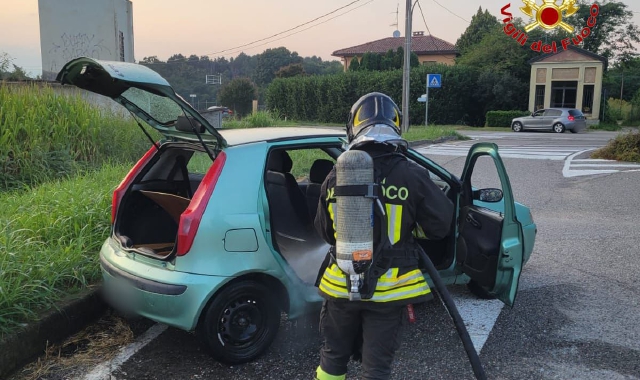 Un vigile del fuoco interviene sull’auto per spegnere le fiamme